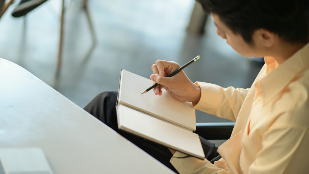 A professional writing his career plan on a notebook.
